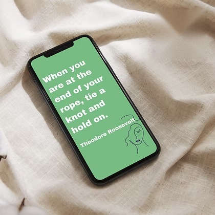 Phone on linen with a green screen quoting Theodore Roosevelt: &ldquo;When you are at the end of your rope, tie a knot and hold on.&rdquo;